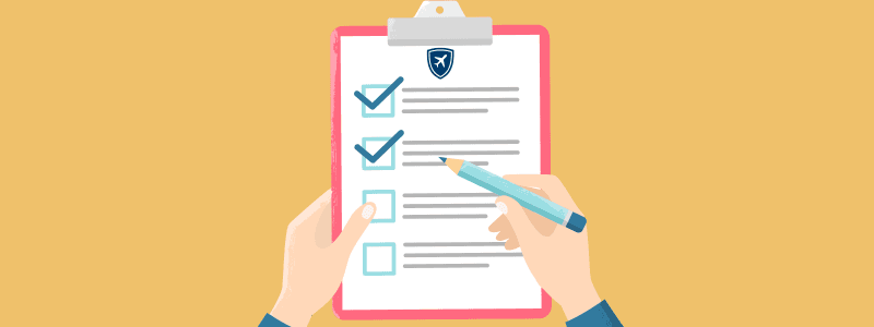 Hands holding a clipboard checklist with blue checkmarks and a small travel-shield badge, symbolizing IEC Canada insurance requirements.